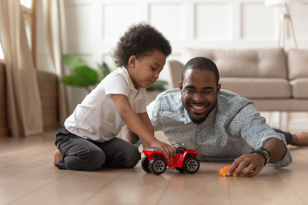 man and boy playing with cars on floor