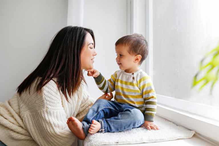 mom talking to toddler by window